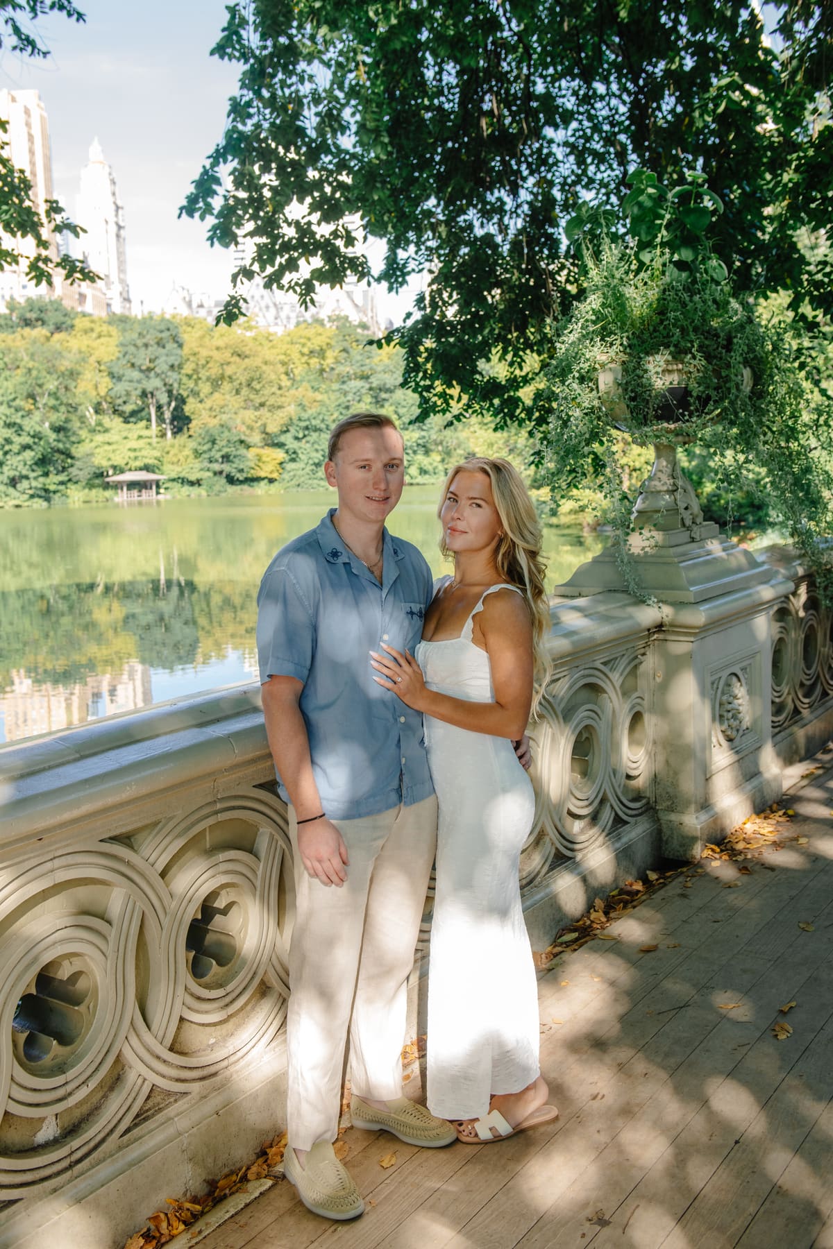 Annabel and her fiancé standing on a stone bridge beside a lake.